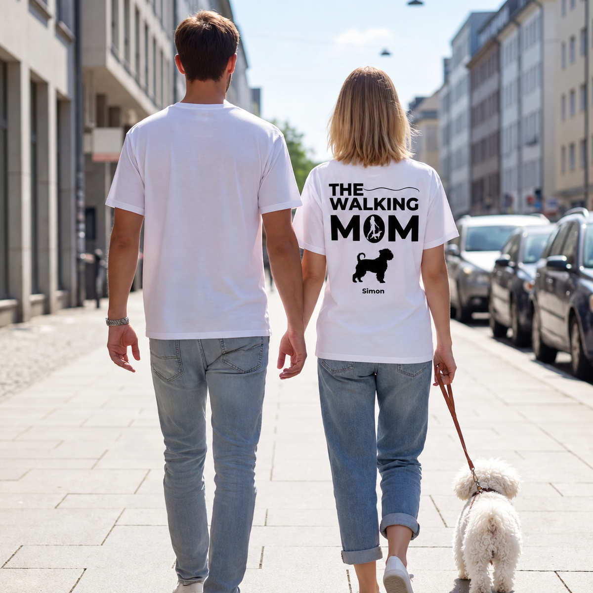 Deux personnes en T-shirts blancs avec l'inscription "THE WALKING MOM" et un chien, dans la rue.