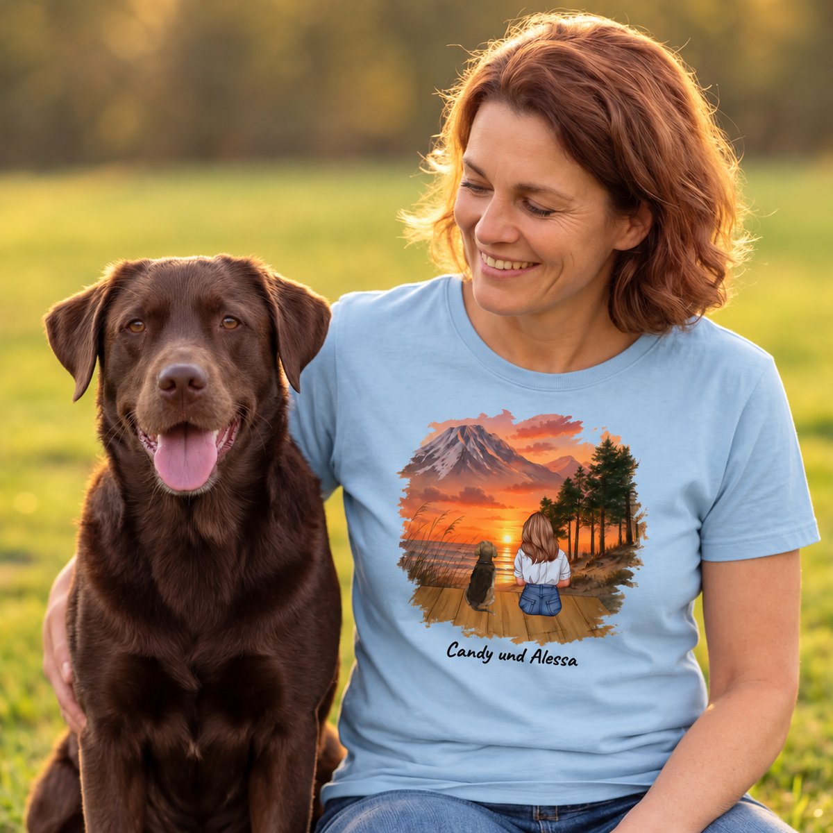 T-shirt bleu avec impression graphique d'une femme et de son chien devant un paysage de montagne.