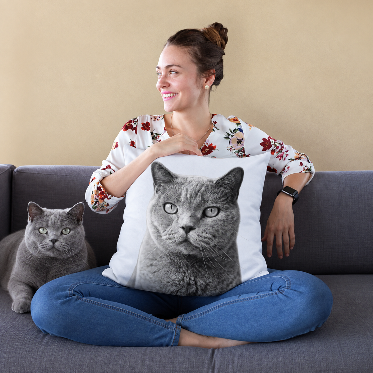 Coussin avec portrait de chat noir et blanc, personne assise sur un canapé tenant le coussin.