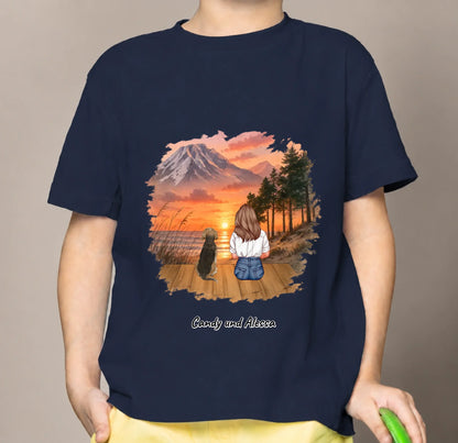 T-shirt enfant bleu avec graphique d'une personne assise et d'un chien dans un paysage au coucher du soleil.