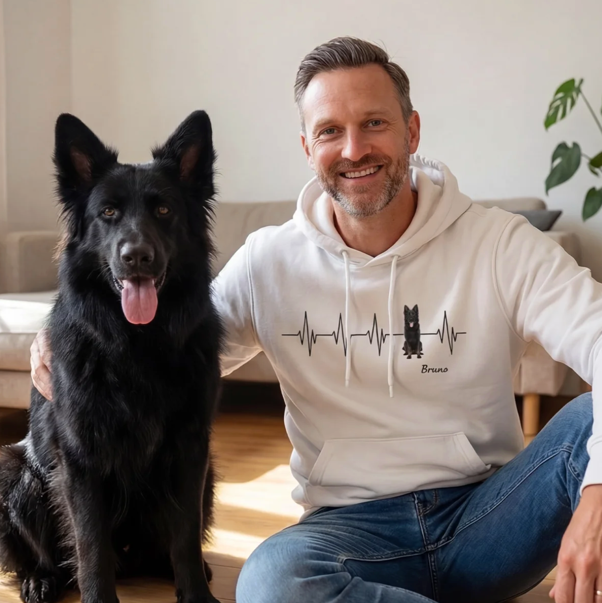 Sweat à capuche blanc avec motif battement de cœur et chien, homme assis à côté d'un chien noir.