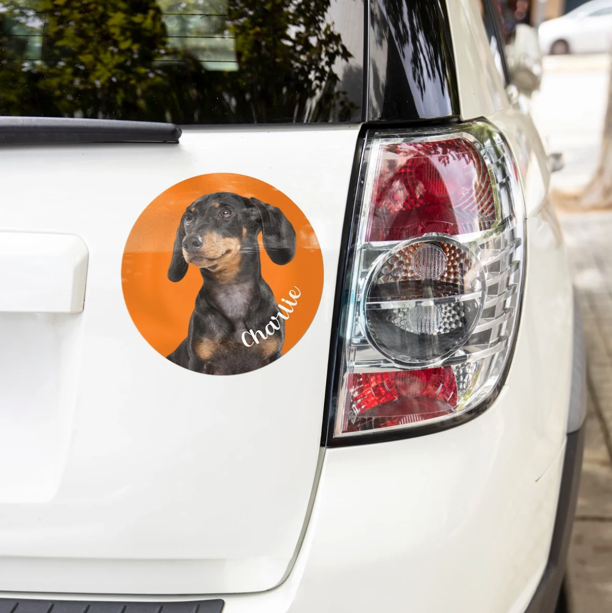 Autocollant de voiture personnalisé avec image d'un teckel sur fond orange, collé sur une voiture blanche.