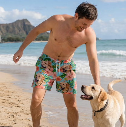 Homme sur la plage portant un short de bain coloré à motifs de chiens et de fleurs. Un labrador joue dans le sable à côté.