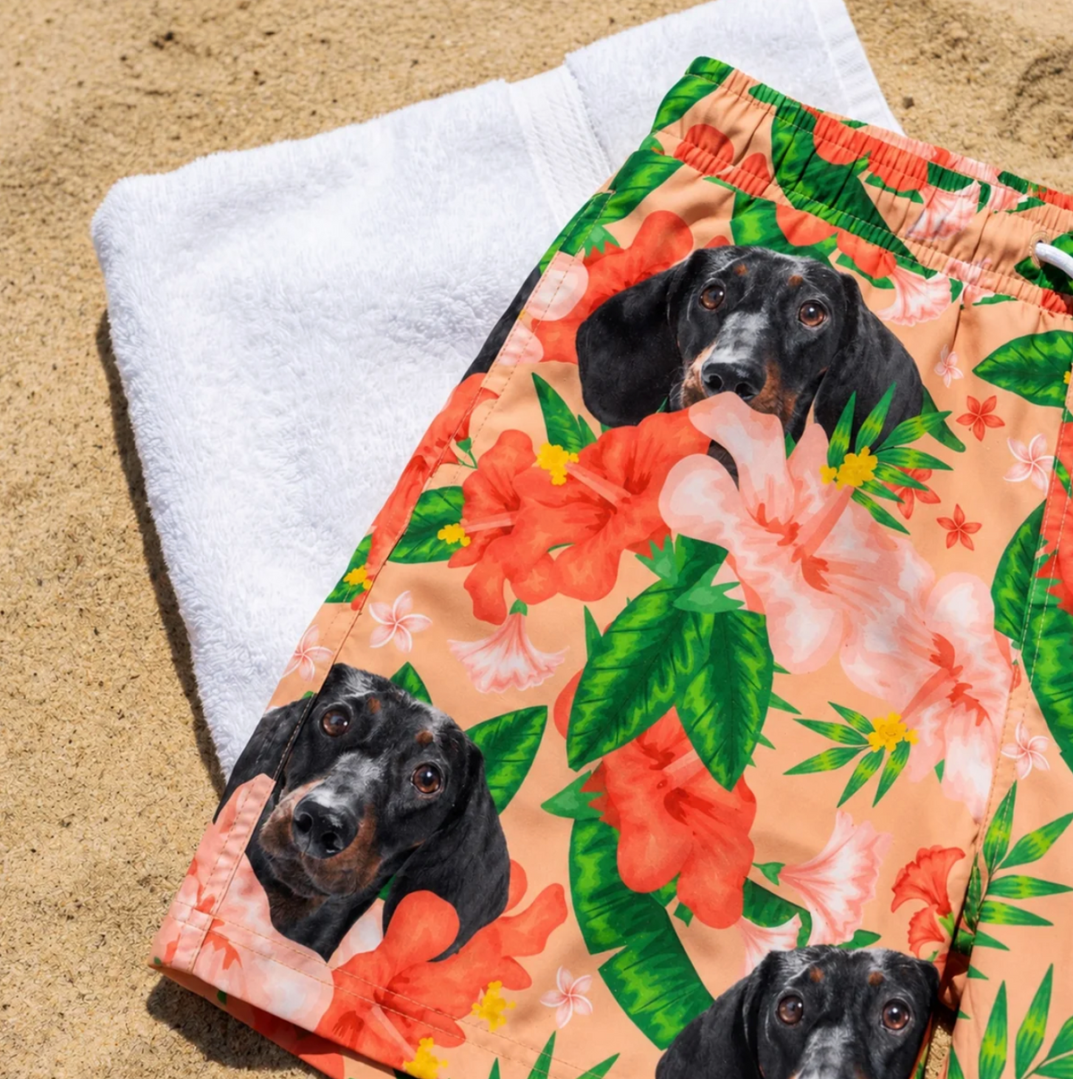Short de bain personnalisé à motifs floraux et imprimé chien posé sur une plage de sable.