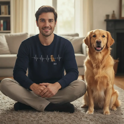 Homme assis sur le tapis du salon portant un sweat-shirt noir avec motif battement de cœur, un golden retriever à côté.