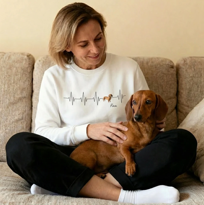 Sweat-shirt blanc avec motif battement de cœur et un chien, femme souriante assise sur un canapé avec un teckel.