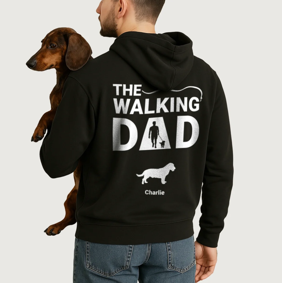 Sweat à capuche noir avec impression personnalisée "The Walking Dad" et motifs de chiens. Porté par un homme avec un chien.