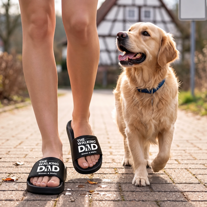 Claquettes noires avec imprimé "THE WALKING DAD", portées lors d'une promenade avec un golden retriever.