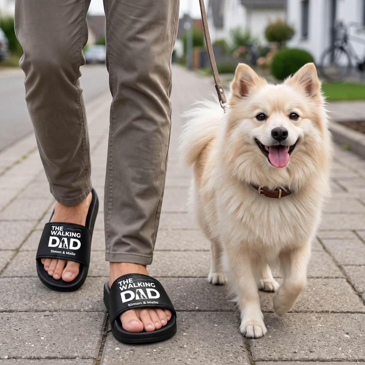 Personne portant des claquettes noires personnalisées avec l'imprimé "THE WALKING DAD", promenant un chien.